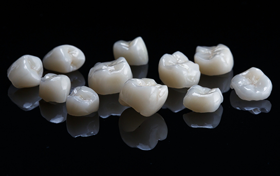 Mulitple tooth colored dental crowns against a black background