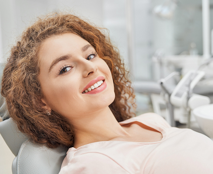 Smiling woman leaning back in the dental chair