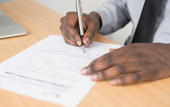 Person filling out paperwork at a table