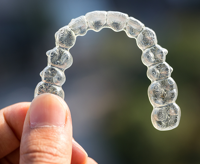 Hand holding an Invisalign clear aligner in Ocoee