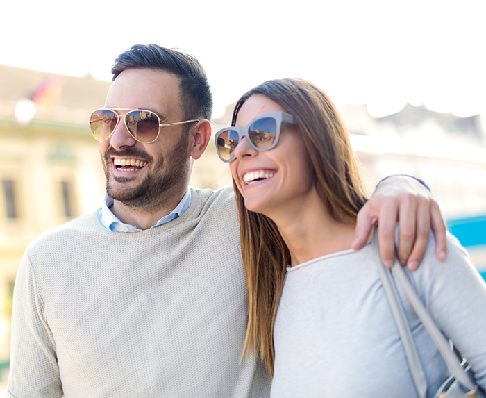 Man and woman smiling in the sun after replacing missing teeth in Ocoee