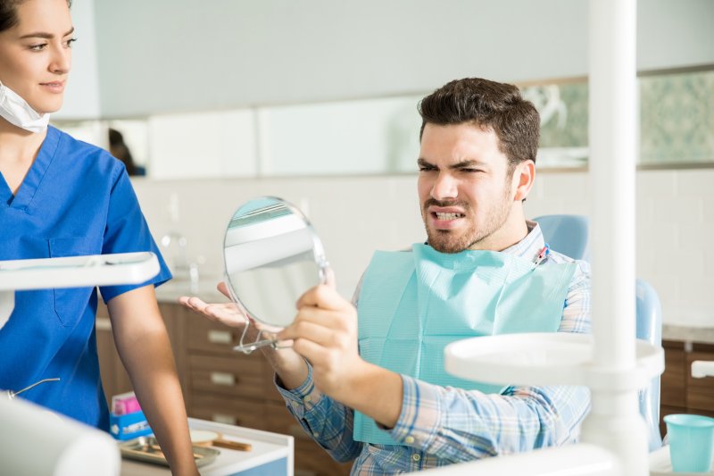 An upset man in a dental clinic checking his teeth