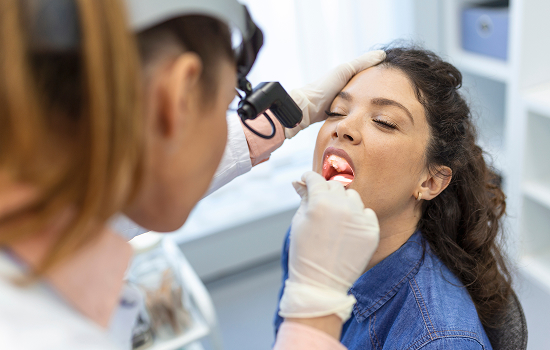 Young boy in the dental chair smiling at his dentist with his mother sitting next to him